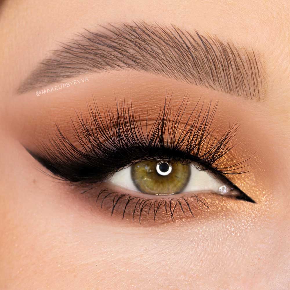 A close-up of an eye with a green iris, bold black winged eyeliner, long vegan-friendly glamnetic lashes in Vacay, a well-defined brow, and shimmering copper eyeshadow. - Product image