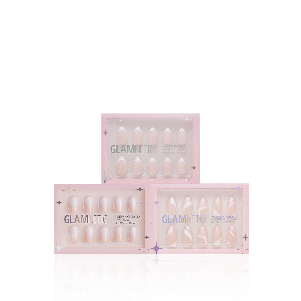 Three boxes of glamnetic Timeless Tips press-on nails, in shades like Marshmallow Swirl, are stacked in a triangle on a white background. Each light pink box displays glossy white or pale pink nails through a transparent window. - Product image