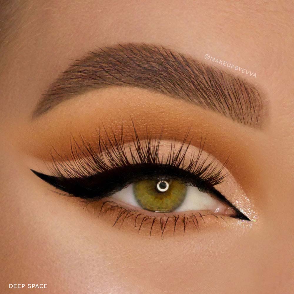 A close-up of an eye with a green iris, bold black winged liner created with the glamnetic Magnetic Eyeliner Pen, voluminous lashes with strong hold, a groomed brow, and eyelids adorned in warm brown and beige eyeshadow.